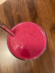 beet smoothie in a glass with metal straw