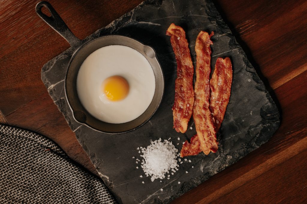 egg in a pan and three strips of bacon