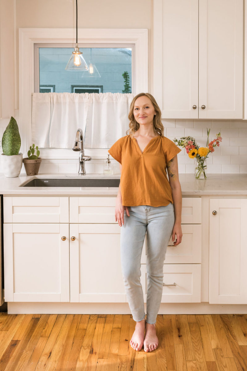 about revel + thrive. Woman standing in kitchen smiling
