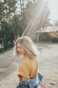 woman smiling with sun rays above her