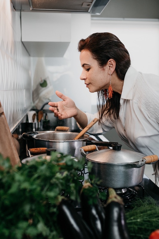 woman smelling aroma from pot on the stove