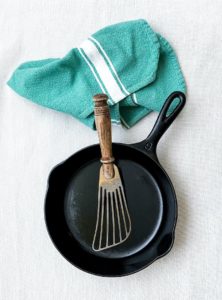 cooking healthy food with cast iron pan with green towel and spatula