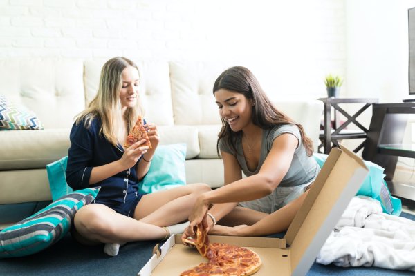 two women eating pizza and smiling