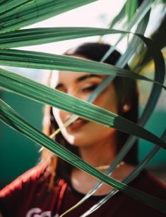 woman looking through leaves on a plant