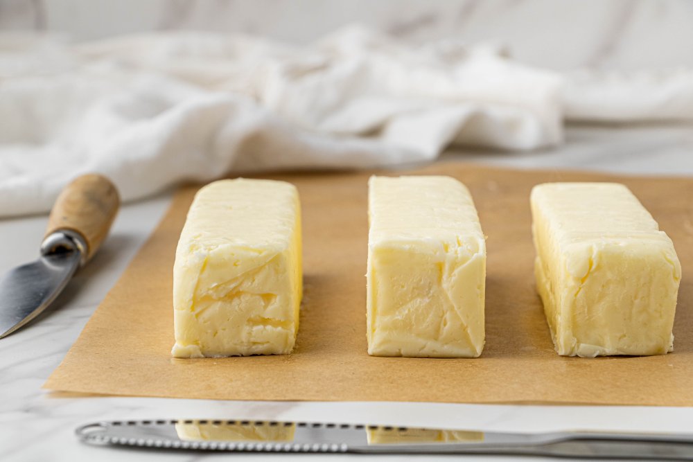 three sticks of butter on a cutting board. revel + thrive